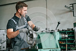 Operating manufacturing equipment. Man in uniform is in workstation developing details of agriculture technique