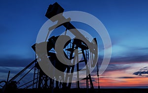 Operating oil and gas well profiled on sunset sky