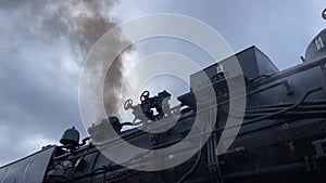 Operating steam locomotive on railway station. Old black steam train with smoke