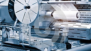 The operation of automatic plastic bag production machine with lighting effect. Close-up of the roller of the plastic bag producti