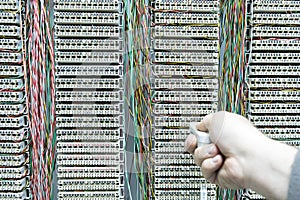 Operator installing telephone switchboard with cables