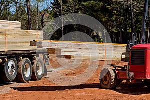 An operator of a lift manipulator unloads wooden building material delivered to a construction site using a lift