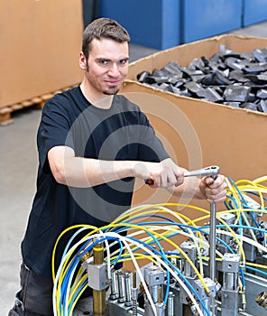 Operator repairs a machine in an industrial plant with tools - p