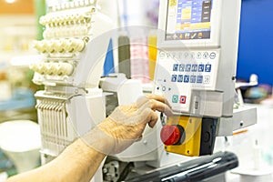 Operator or tailor working on control panel of modern and automatic high technology sewing or embroidery machine for textile -