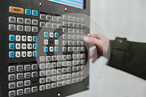 Operator use hand turns dial switch control at panel of CNC lathe machine at factory. Close up of control panel.