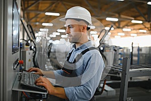 Operator wearing safety hat behind control panel on a factory