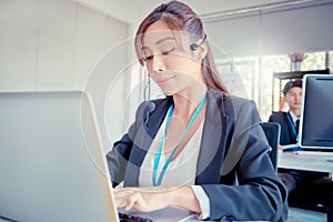 Operators in Call center service talking to customer on the headphone while working on laptop for customer support