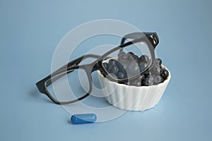 Ophthalmic concept close up. Glasses, blueberries and blueberry vitamin on a blue background. Natural products to improve and