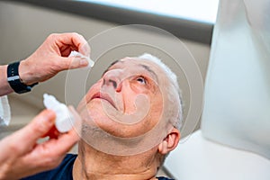 Ophthalmologist applies drops to dilate the pupil to a man