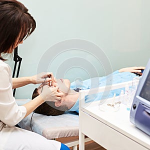 Ophthalmologist doctor in exam optician laboratory with male patient. Men eye