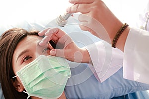 An ophthalmologist examines the eyes of a patient lying in bed.