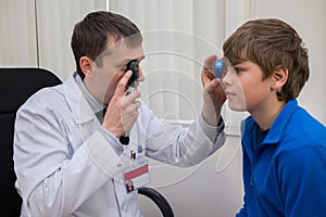 ophthalmologist examines the eyes of a teenage boy