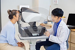 Ophthalmologist examining eyesight modern machine for middle aged asian woman. Checking eye vision by optician health examination