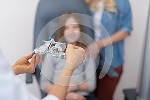 Ophthalmologist hands holding optometric trial frame for child