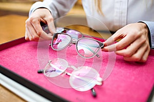 Ophthalmologist hands showing eyeglasses to customer in optic shop