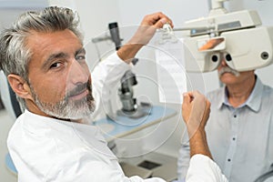 ophthalmologist holding text for patient to read through phoropter