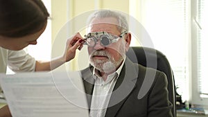 ophthalmologist makes selection of lenses, diagnoses a elderly man's vision.