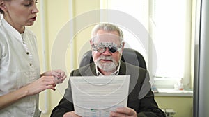 ophthalmologist makes selection of lenses, diagnoses a elderly man's vision.