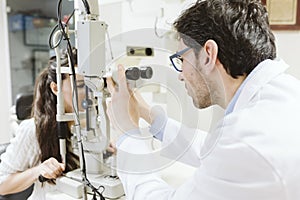 Ophthalmologist man examining young woman eyes in clinic