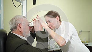 ophthalmologist measures interpupillary distance of elderly man. pupillometer