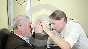 ophthalmologist measures interpupillary distance of elderly man. pupillometer