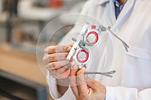 Ophthalmologist with optometrist trial frame in ophthalmological clinic, Optometrist checking trial frame in optical shop photo