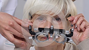 Ophthalmologist putting phoropter on elderly woman eyes, vision examination