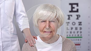 Ophthalmologist supporting elderly woman with blurred vision, planned check-up