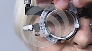 Ophthalmologist taking off lens from optical trial frame, glasses prescription