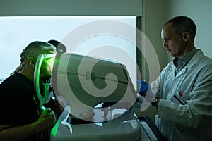 Ophthalmologist treating glaucoma on a senior man using laser machine