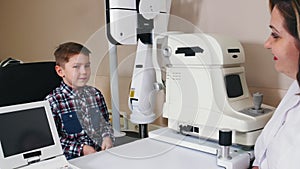 Ophthalmologist treatment - mature woman doctor talking to a little boy