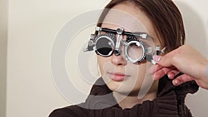 Ophthalmologist is trying on lenses in a trial frame on face of woman