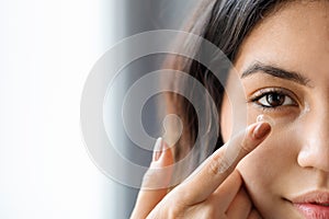 Ophthalmology Care Concept. Young arab woman putting contact lens in her eye