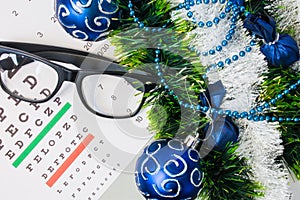 Ophthalmology or optometry Christmas and New Year with decorations. Eyeglasses and table for measure visual acuity lying near arti