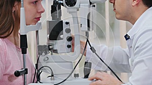 Ophthalmology treatment - a doctor checking young woman`s visual acuity with a special machine in a spacious cabinet