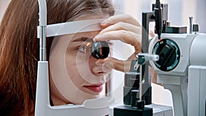 Ophthalmology treatment - a young woman with pink lips checking her visual acuity with a light of special big optometry