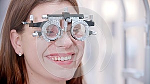 Ophthalmology - a young smiling woman with a device for vision test on her nose