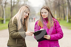 Opinion poll. A woman interviewing people, conducting survey standing outdoor