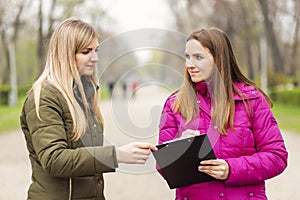 Opinion poll. A woman interviewing people, conducting survey standing outdoor