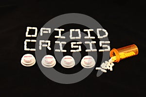 Opioid crisis spelled out with white pills above several prescription bottle lids on a black background