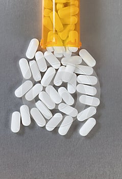 Opioid tablets spilling out of bottle onto stainless steel table