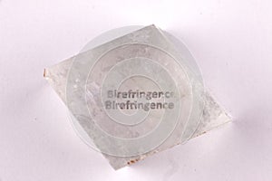 Optical birefringence demonstrated using a text using a natural double spar calcite crystal