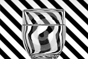 Oblique black and white lines reflected in a glass of water photo