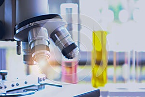 Optical microscope use in chemical experiment, phamaceutical research, and medical analysis with blurred background of laboratory.