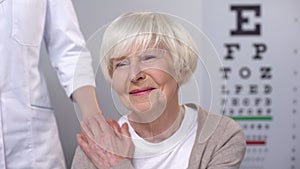 Optician comforting elderly woman during eyesight examination, health care