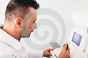 Optician examining patient`s eye on a machine.