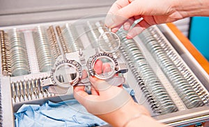 Optician female hands choose lenses from set of corrective lens indicating on the plates of the shape: concave, convex, cylindrica