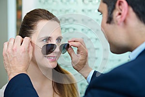 optician fitting prescription sunglasses on client