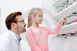 Optician and girl choosing glasses at optics store