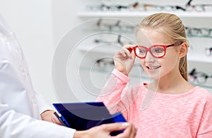 Optician and girl choosing glasses at optics store